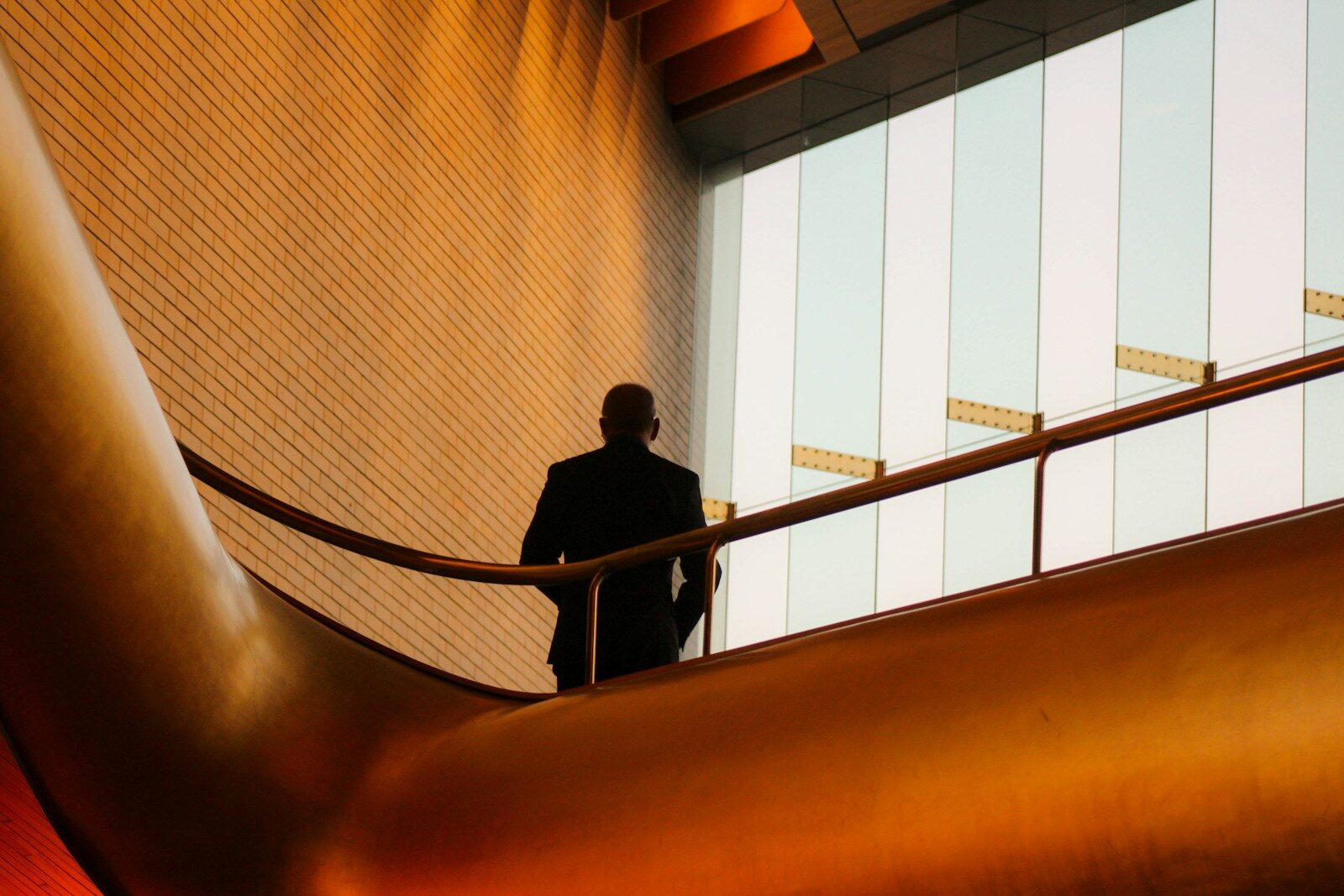 A person in a dark suit on a balcony with a curved gold railing